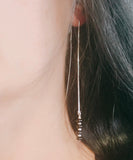 woman wearing long ear thread earrings