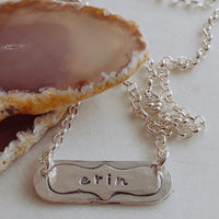 hand stamped bar necklace next to rock